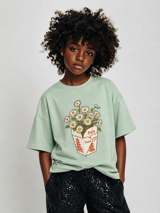 Person wearing a light green t-shirt with a floral design on a plain background