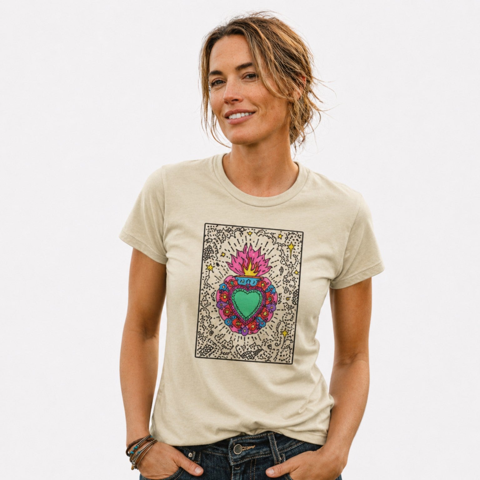 Woman wearing a beige Sacred Heart graphic t-shirt featuring folk art-inspired heart artwork celebrating tradition, creativity, and cultural expression.