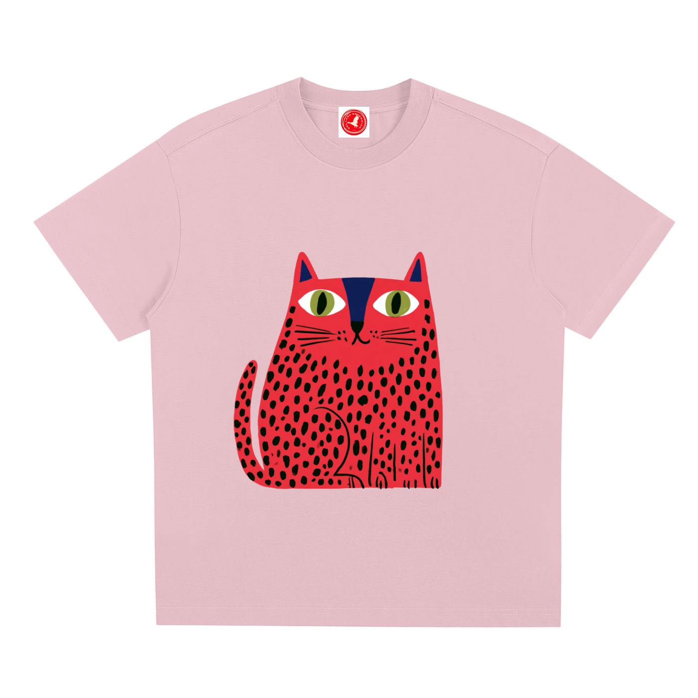 A light pink short-sleeve crewneck t-shirt featuring a stylized graphic of a red cat with black spots and green eyes on the front, displayed against a solid white background.