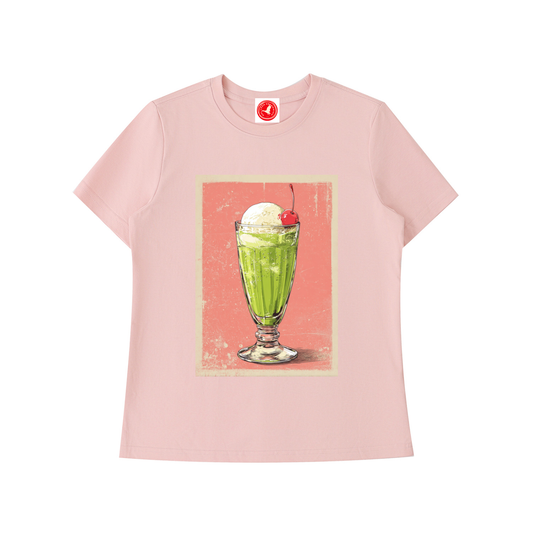 Pink t-shirt with a graphic of a green milkshake and cherry on a white background
