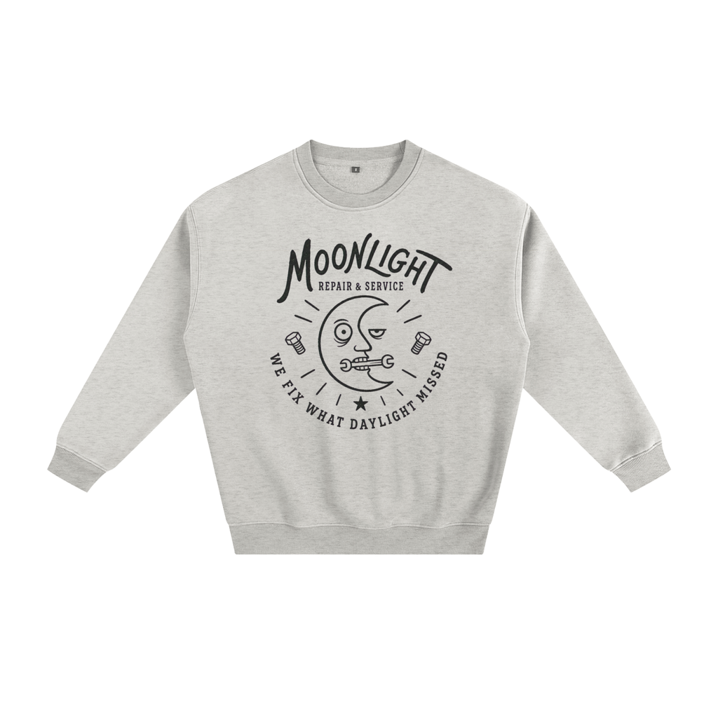 A light heather gray crewneck sweatshirt with a black graphic print on the front featuring a moon face, the text 'MOONLIGHT', and 'WE FIX WHAT DAYLIGHT MISSED'.