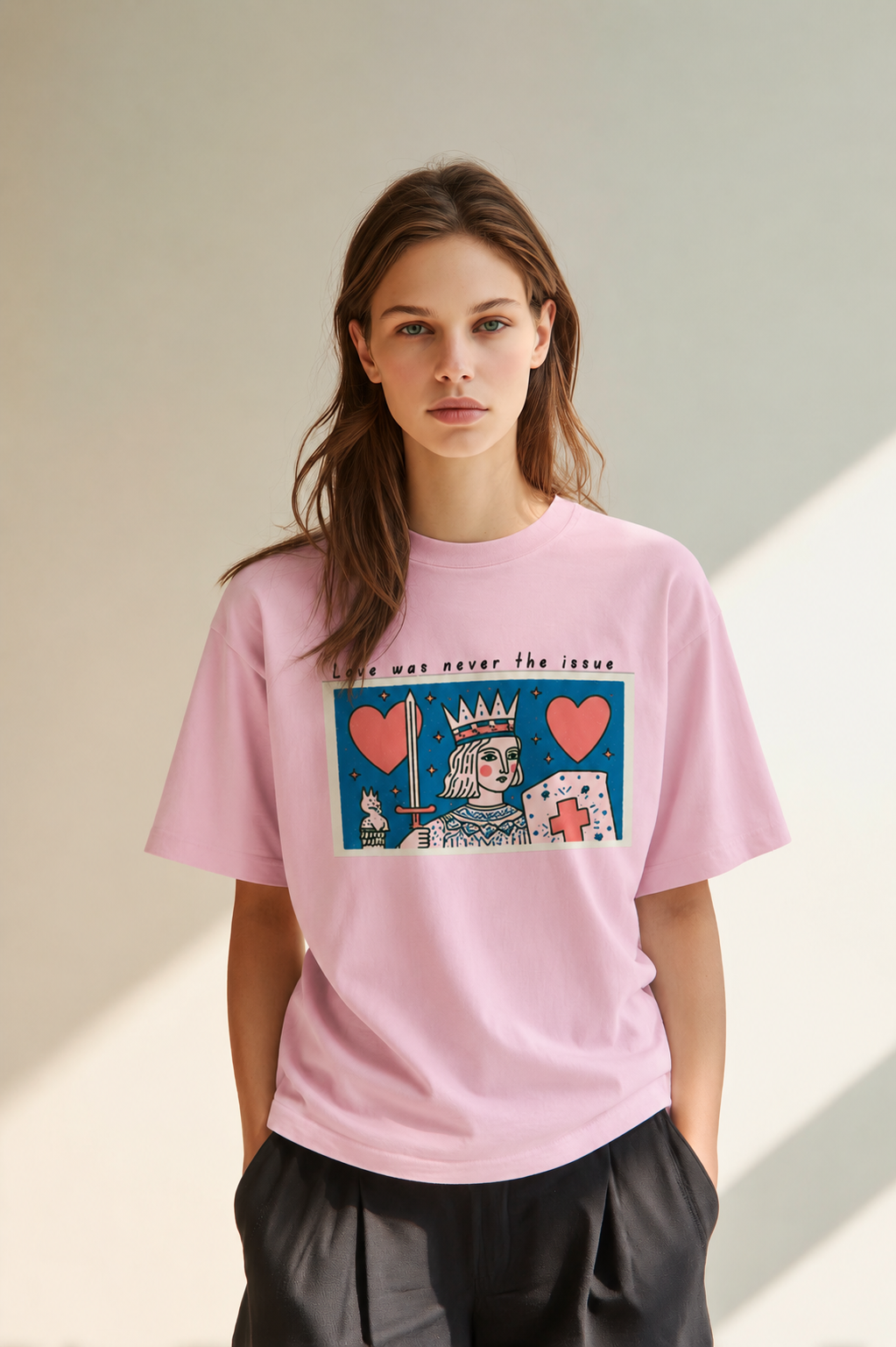 Woman wearing the Love Was Never the Issue pink oversized graphic t-shirt with vintage-inspired crowned figure artwork and relaxed streetwear fit.