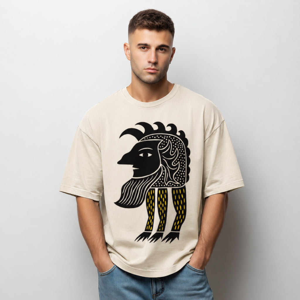 Man wearing a beige Abstract Folk Creature graphic t-shirt featuring artistic folk-inspired creature artwork and imaginative storytelling design.