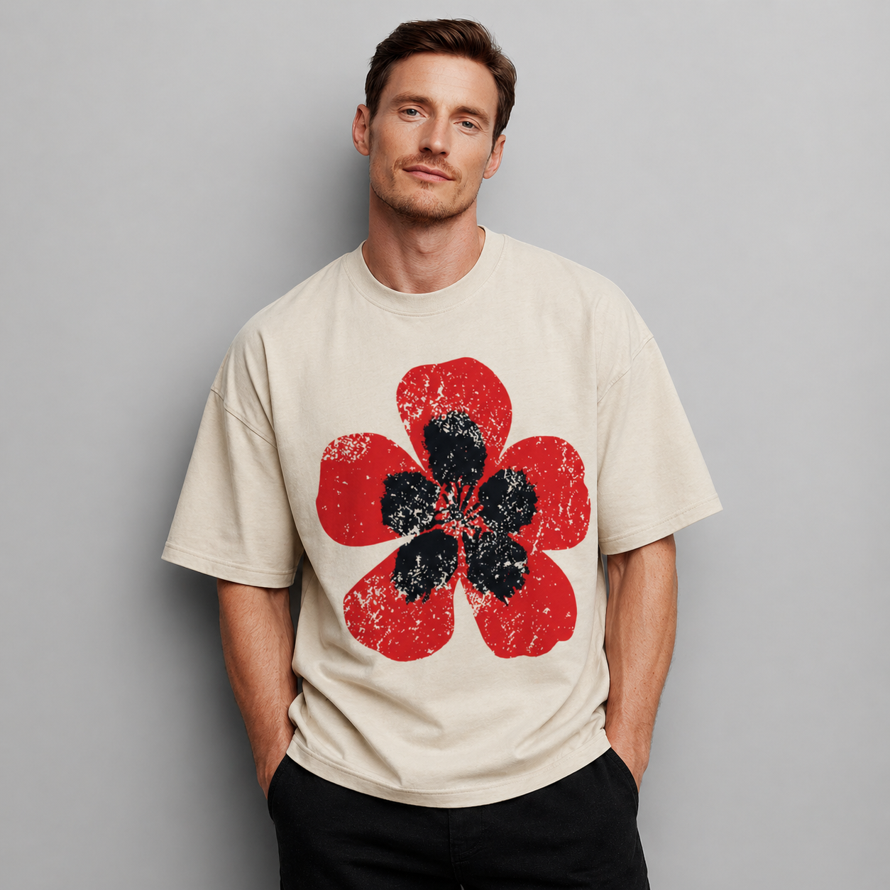 Man wearing a beige t-shirt with a red and black flower design on a gray background