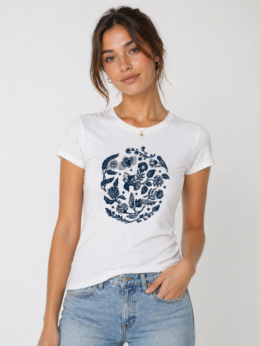Woman wearing a white t-shirt with a blue floral design on a plain background