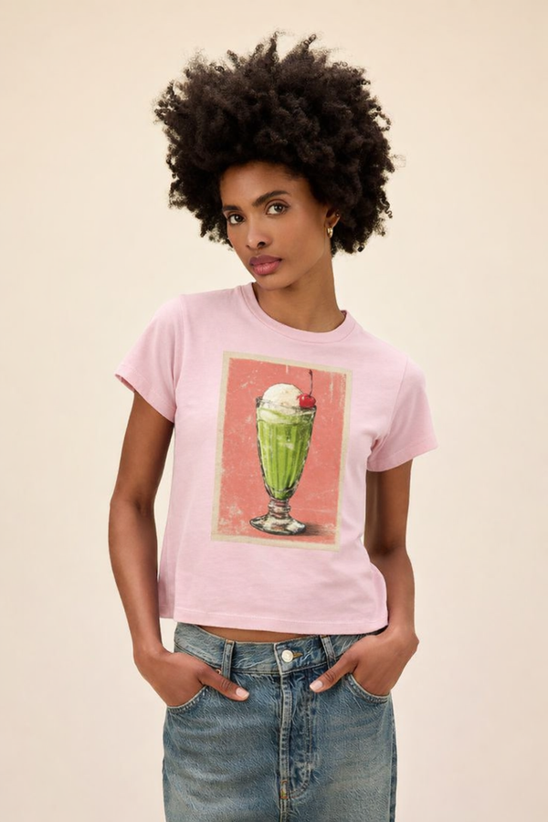 Woman wearing a pink t-shirt with a graphic design of a green ice cream sundae.
