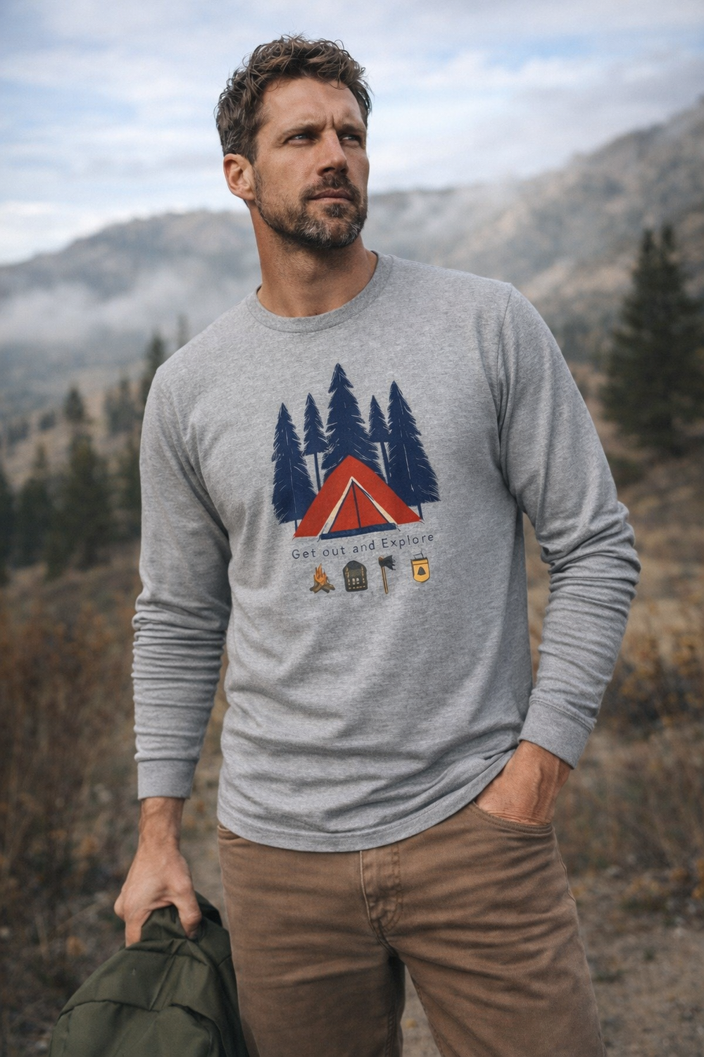 Man wearing a gray sweatshirt with a nature-themed design in a mountainous landscape