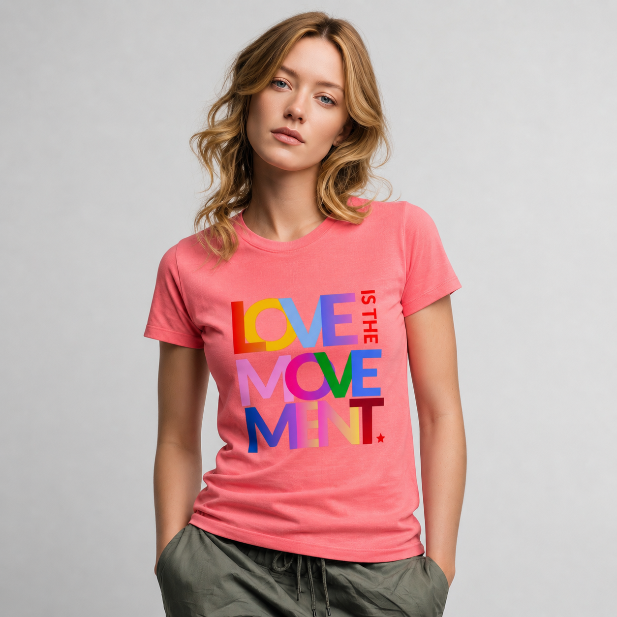 Woman wearing a pink Love Is the Movement graphic t-shirt featuring uplifting artwork inspired by kindness, unity, and positive self-expression.