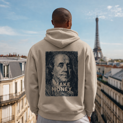 Person wearing a hoodie with a graphic of Benjamin Franklin and 'MAKE MONEY' text, standing in front of the Eiffel Tower.
