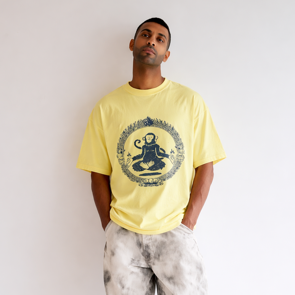 Man wearing a yellow t-shirt with a design and light-colored pants on a white background