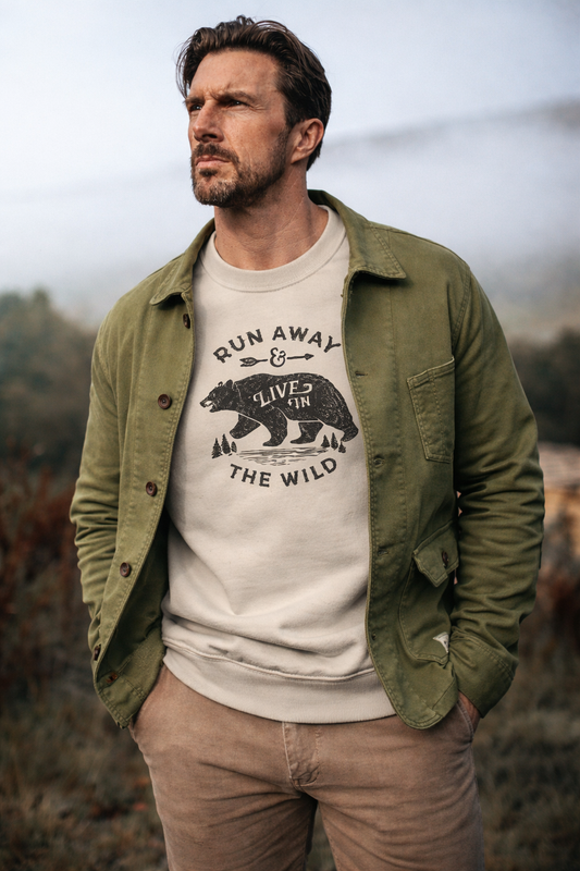 Man wearing a green jacket over a white t-shirt with a bear graphic and text, standing outdoors.