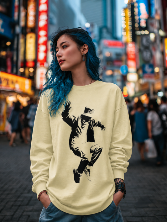 Person wearing a light yellow sweatshirt with a graphic design in a city street at night.