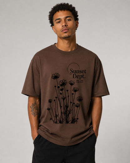 Man wearing a brown t-shirt with black floral design and 'Sunset Dept.' text on a gray background
