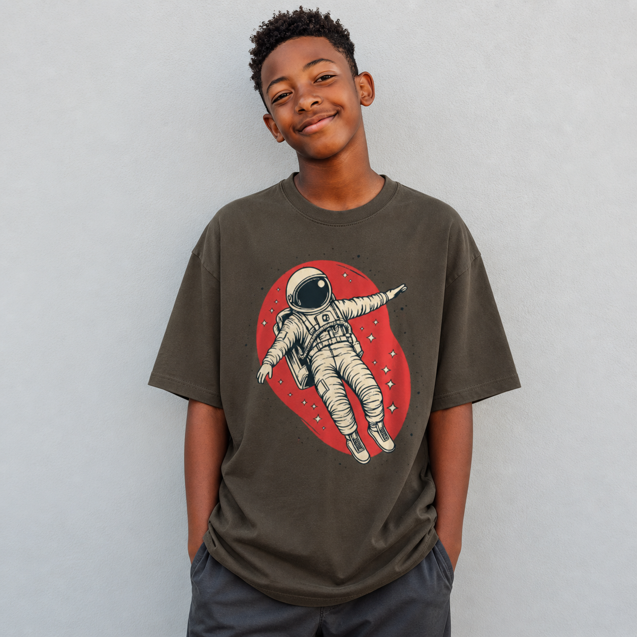 Child wearing a t-shirt with an astronaut graphic on a plain background